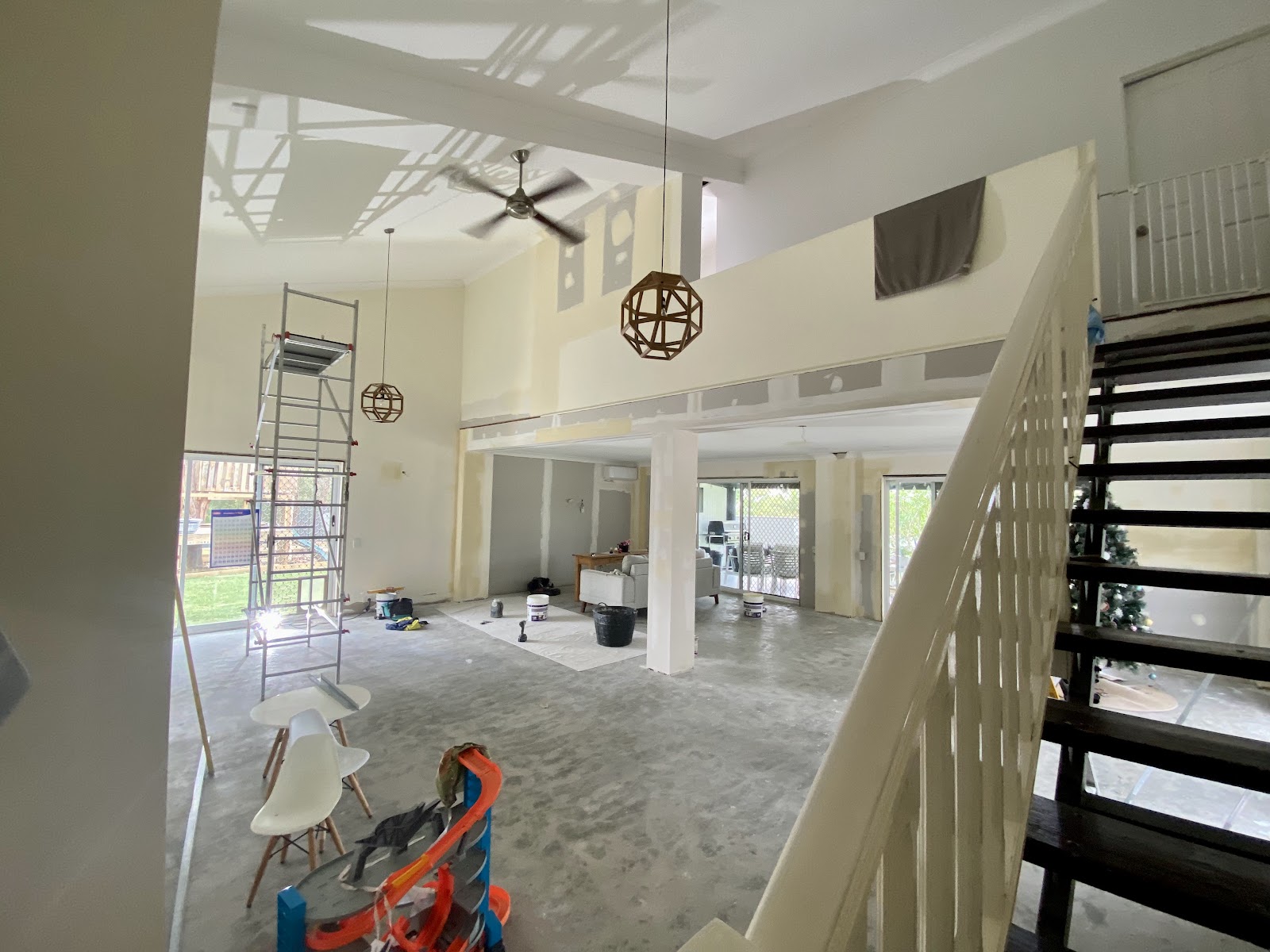Double-height void above a staircase with freshly set plaster and scaffolding